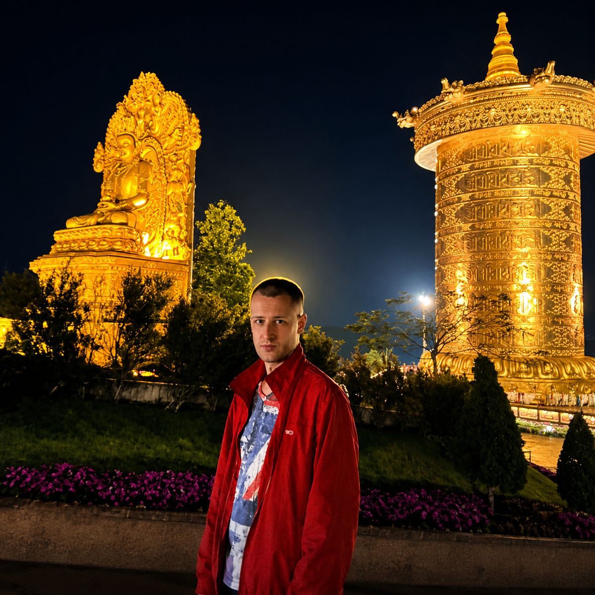 Valentin Roganov before a golden prayer wheel and Buddha at night